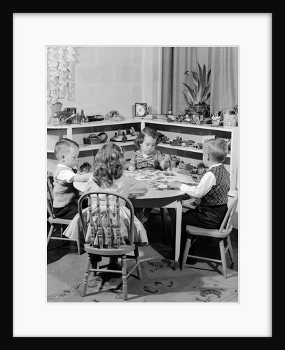 1950s 4 pre-school age children seated at small round table putting together jigsaw puzzle by Anonymous