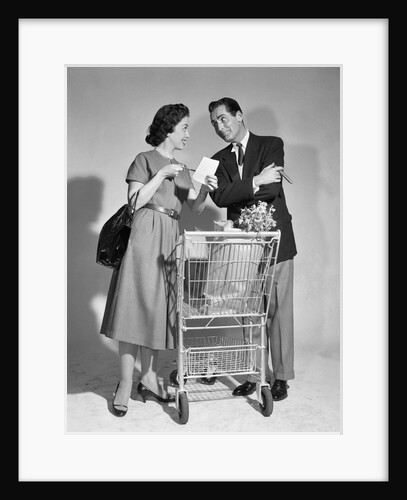 1950s couple man woman shopping cart reviewing grocery list man has cigar in hand by Anonymous