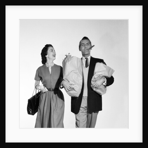 1950s couple walking woman smiling at man carrying grocery bags smoking cigar by Anonymous