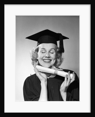 1950s smiling woman teenage girl eyes closed holding diploma graduate wearing cap gown by Anonymous