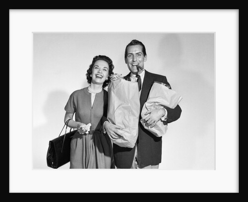 1950s couple smiling woman man carrying grocery bags smoking cigar looking at camera by Anonymous