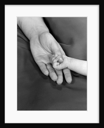 1950s close-up of baby holding mother's thumb by Anonymous