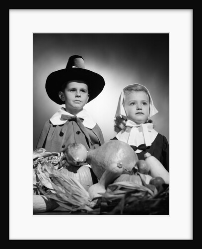 1950s boy & girl in pilgrim costumes with harvest arrangement on table by Anonymous