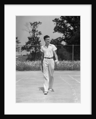 1930s man walking across tennis court holding tennis racket & balls by Anonymous