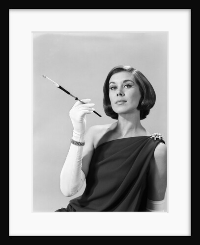1960s formally elegantly dressed young woman arrogant expression holding long cigarette holder wearing long white gloves by Anonymous