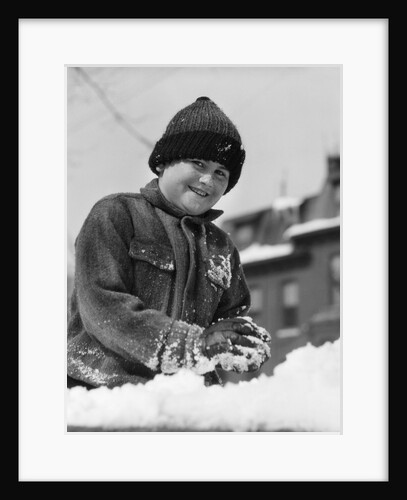 1920s 1930s smiling boy playing in snow making snowball looking at camera by Anonymous