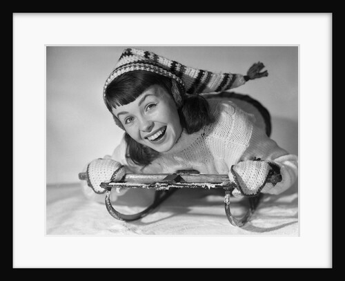1950s smiling young teenage woman posing on sled in winter wool knit clothes looking at camera by Anonymous