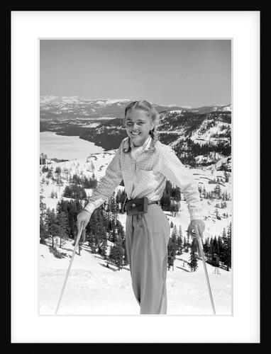 1940s 1950s young blond athletic woman looking at camera smiling standing with ski poles top of mountain by Anonymous