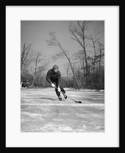 1940s man playing ice hockey on frozen lake controlling puck with stick by Anonymous