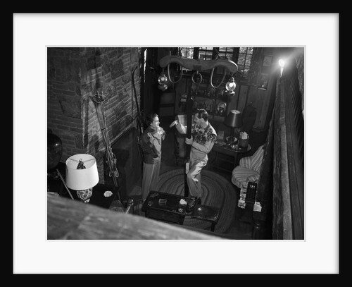 1950s couple man woman wearing sweaters talking in ski lodge by fireplace view from above by Anonymous