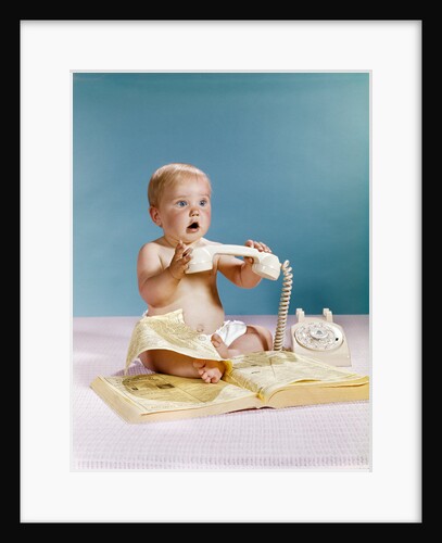 1960s baby surprised facial expression holding telephone hand set over yellow pages phone book directory by Anonymous