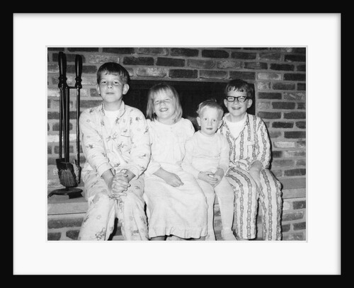 Siblings perch on a hearth in pajamas, ca. 1970. by Anonymous