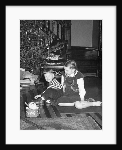 Brother and sister in front of the Christmas tree, ca. 1950 by Anonymous