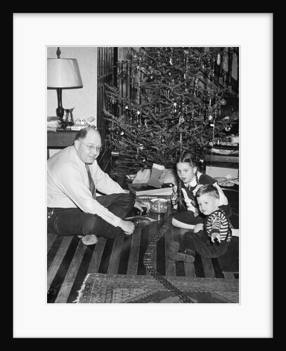 Father with daughter and son in front of Christmas tree, ca. 1950 by Anonymous