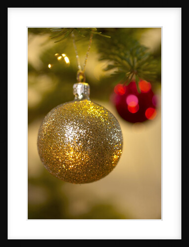 Close-up of a golden hanging Christmas bauble on blurred tree by Anonymous