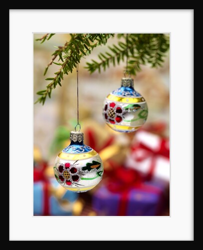 Close-up of decorated hanging baubles against blurred gifts in the background by Anonymous
