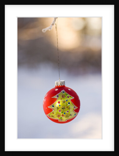 Close-up of golden Christmas tree on red bauble against blurred background by Anonymous