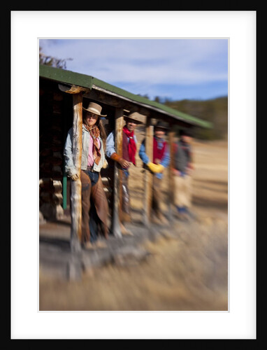 Cowgirls and cowboys outside a cabin by Anonymous