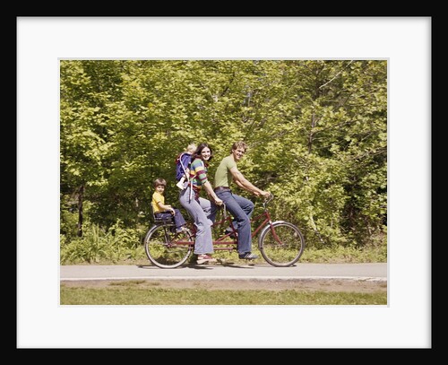 1970s Family On Tandem Bicycle Mother Father Son & Baby Daughter In Backpack Wearing Bellbottom Blue Jeans Looking At Camera by Anonymous