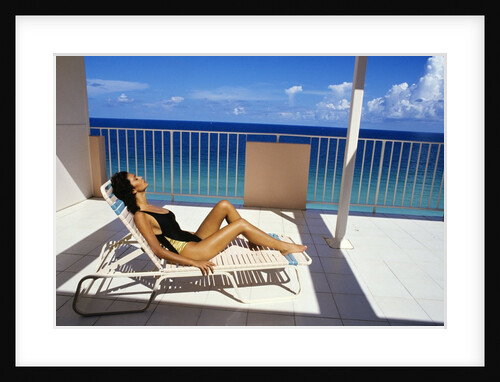 1990s Woman Wearing Black And Gold Bathing Suit Sunbathing On Patio In Deck Chair by Anonymous