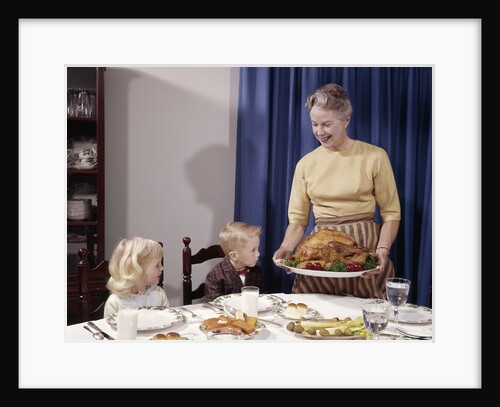 1960s Grandmother Presenting Roasted Turkey To Children At Dining Room Table by Anonymous
