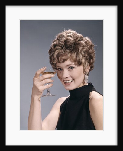1960s Portrait Glamourous Woman In Black Dress Earrings Holding A Cocktail Looking At Camera by Anonymous