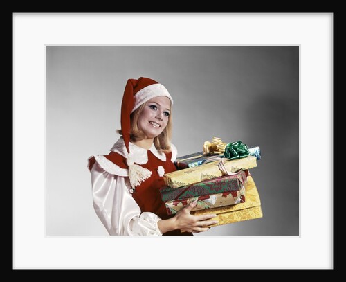 1960s Young Woman In Red And White Santa Helper Costume And Hat Holding Pile Of Wrapped Christmas Presents Studio by Anonymous