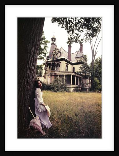 1960s 1970s Woman Standing Beside Tree Front Of Abandoned Haunted Victorian House by Anonymous