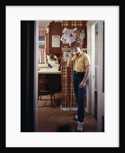 1970s Teenage Boy Talking On Kitchen Wall Phone Telephone by Anonymous