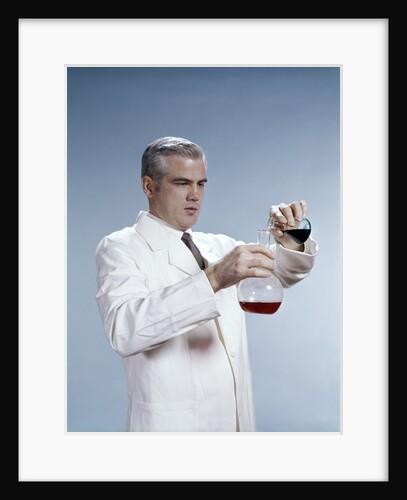 1960s Man Wearing Lab Coat Pouring Liquid From Small Erlenmeyer Flask Into A Larger Flask by Anonymous