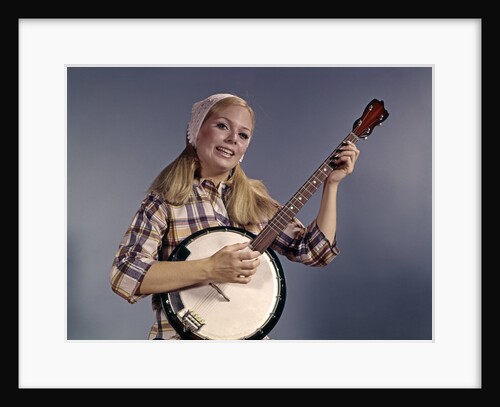 1960s Young Blonde Woman Wearing Plaid Shirt Playing Banjo Singing Folk Music Looking At Camera by Anonymous