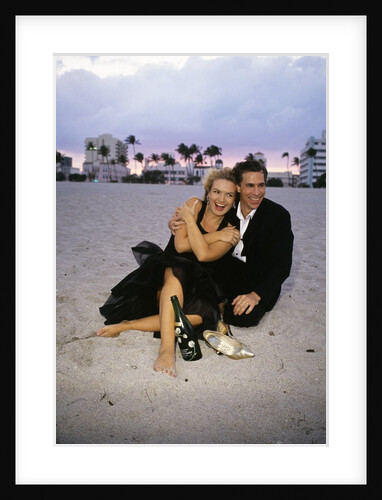 1990s Laughing Couple Man Woman In Formal Wear Sitting Hugging On Beach by Anonymous