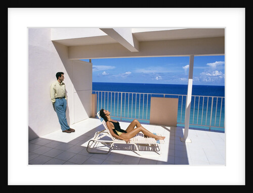 1990s Man And Woman On Sunny Deck Balcony Overlooking The Ocean by Anonymous