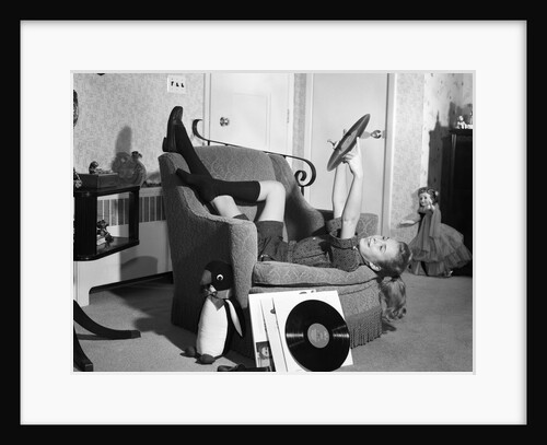 1950s 1960s Teenage Girl Smiling Reclining Upside Down On Chair Holding Vinyl Record Album Listening To Music by Anonymous