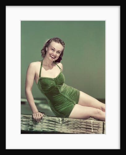1940s Portrait Smiling Woman Wearing Green Velvet Bathing Suit Sitting Posing On Diving Board by Anonymous
