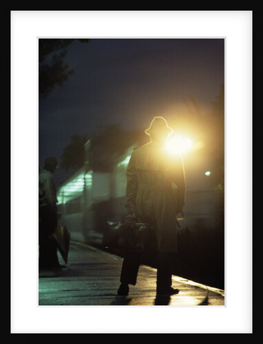 1970s 1980s Anonymous Man Commuter Waiting For Train Silhouetted By Bright Light by Anonymous