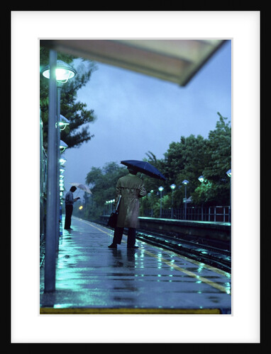 1970s 1980s Anonymous Business Man Holding Umbrella Waiting For A Commuter Train by Anonymous