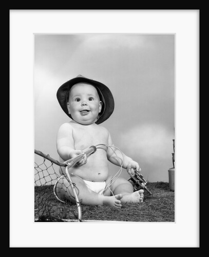 1960s Baby Girl Wearing Fishing Hat Holding Net And Reel Fishing Gear Looking At Camera by Anonymous