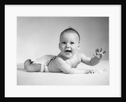 1960s Smiling Baby Wearing Cloth Diaper Lying On Stomach Looking At Camera Arm Raised by Anonymous