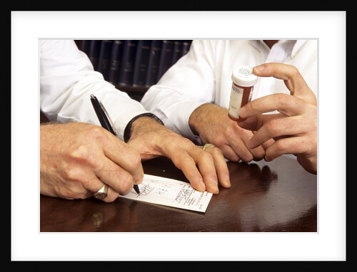 1990s Doctor Writing Refill Prescription For Patient Holding Pill Bottle by Anonymous