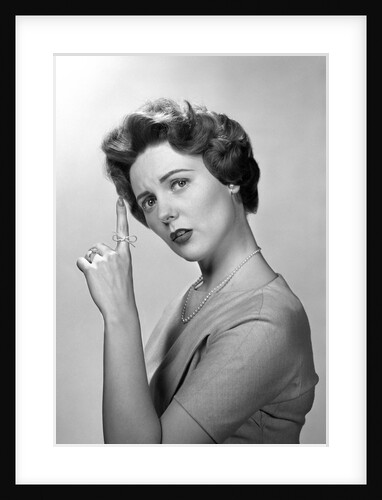1950s Concerned Woman With Reminder String Knot Tied On Finger Of Hand To Help Remember Something Looking At Camera by Anonymous