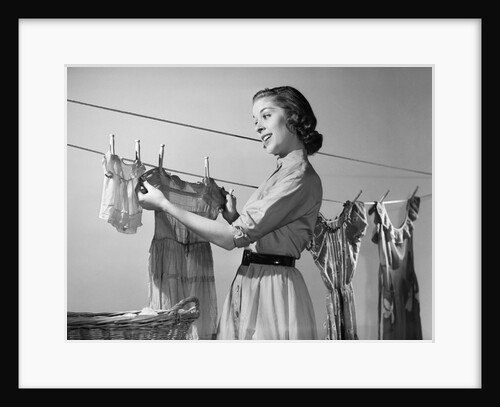 1950s Smiling Woman Housewife Hanging Wash Child Dress On Clothesline To Dry by Anonymous