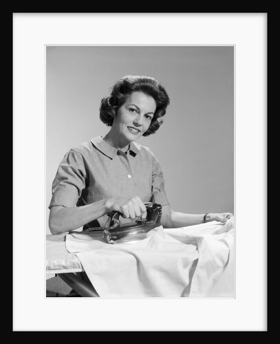 1950s Smiling Woman Housewife Ironing Shirt Looking At Camera by Anonymous