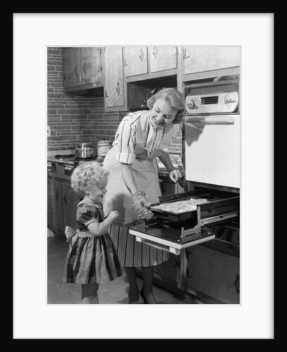 1950s Smiling Mother Daughter In Kitchen Broiling Pork Chops by Anonymous