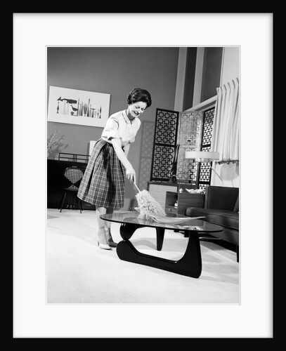1950s 1960s Woman Wearing A White Blouse & Plaid Skirt Dusting With A Feather Duster A Glass Top Coffee Table by Anonymous