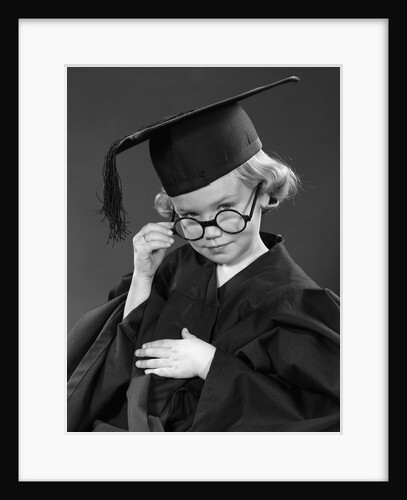 1950s Little Blond Girl Wearing Scholarly Glasses Graduation Cap And Gown Looking At Camera by Anonymous