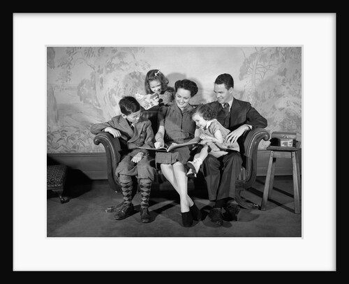 1930s 1940s Family Sitting On Couch Looking Reading Book Together by Anonymous