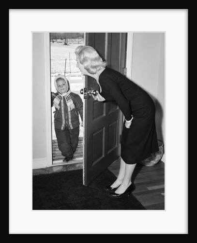 1950s Blonde Mom Opening Front Door To Let In Child Dressed Winter Snow Suit Scarf Hat Can See Snow Scene Through Door by Anonymous
