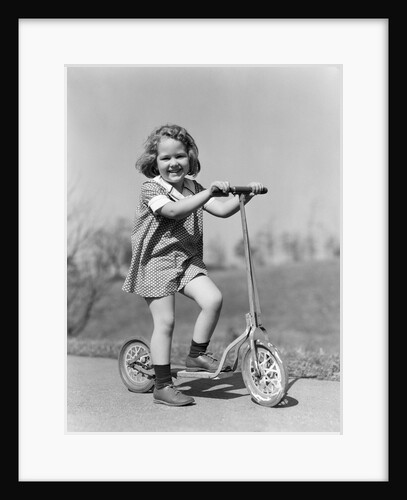 1930s Smiling Girl Playing On Scooter On Sidewalk Looking At Camera by Anonymous