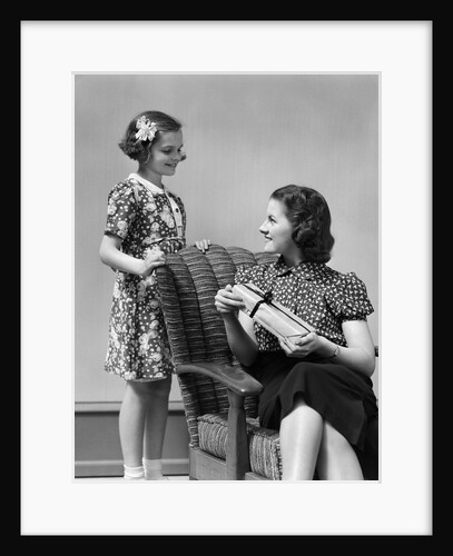 1930s Teenage Girl Daughter Giving A Gift Wrapped Present To Woman Mother Sitting In A Chair by Anonymous